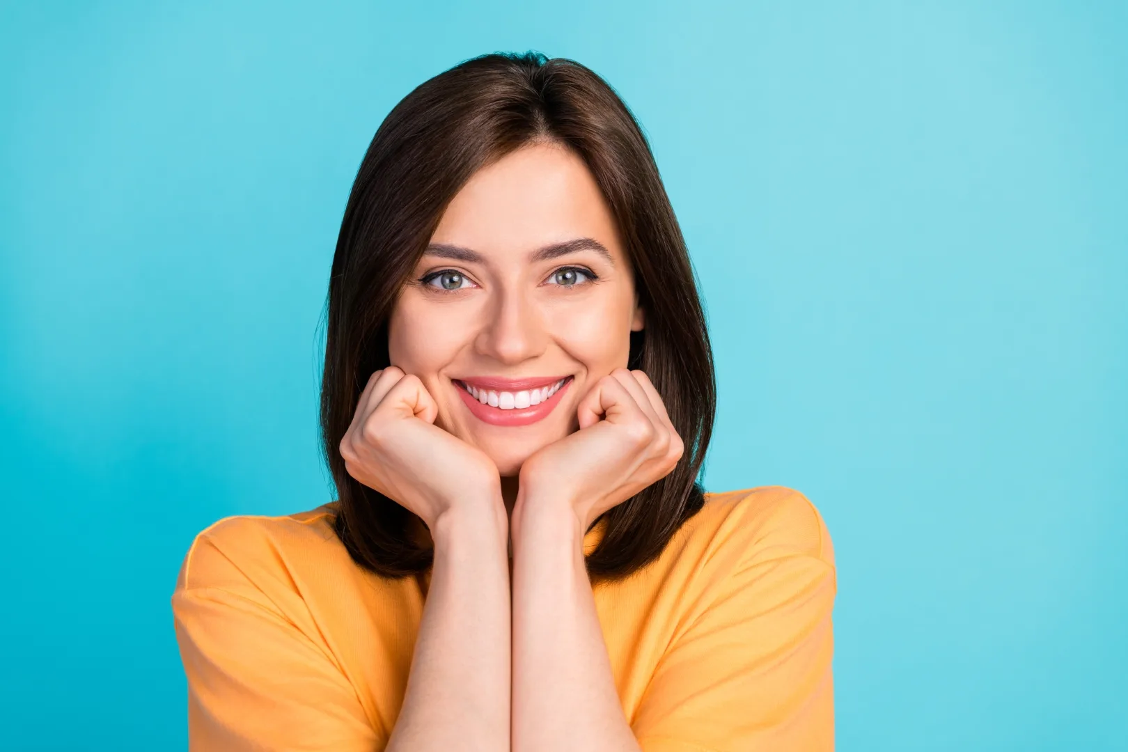 Portrait of good mood pretty woman long hairstyle wear yellow t-shirt toothy smiling arms on cheekbones isolated on blue color background
