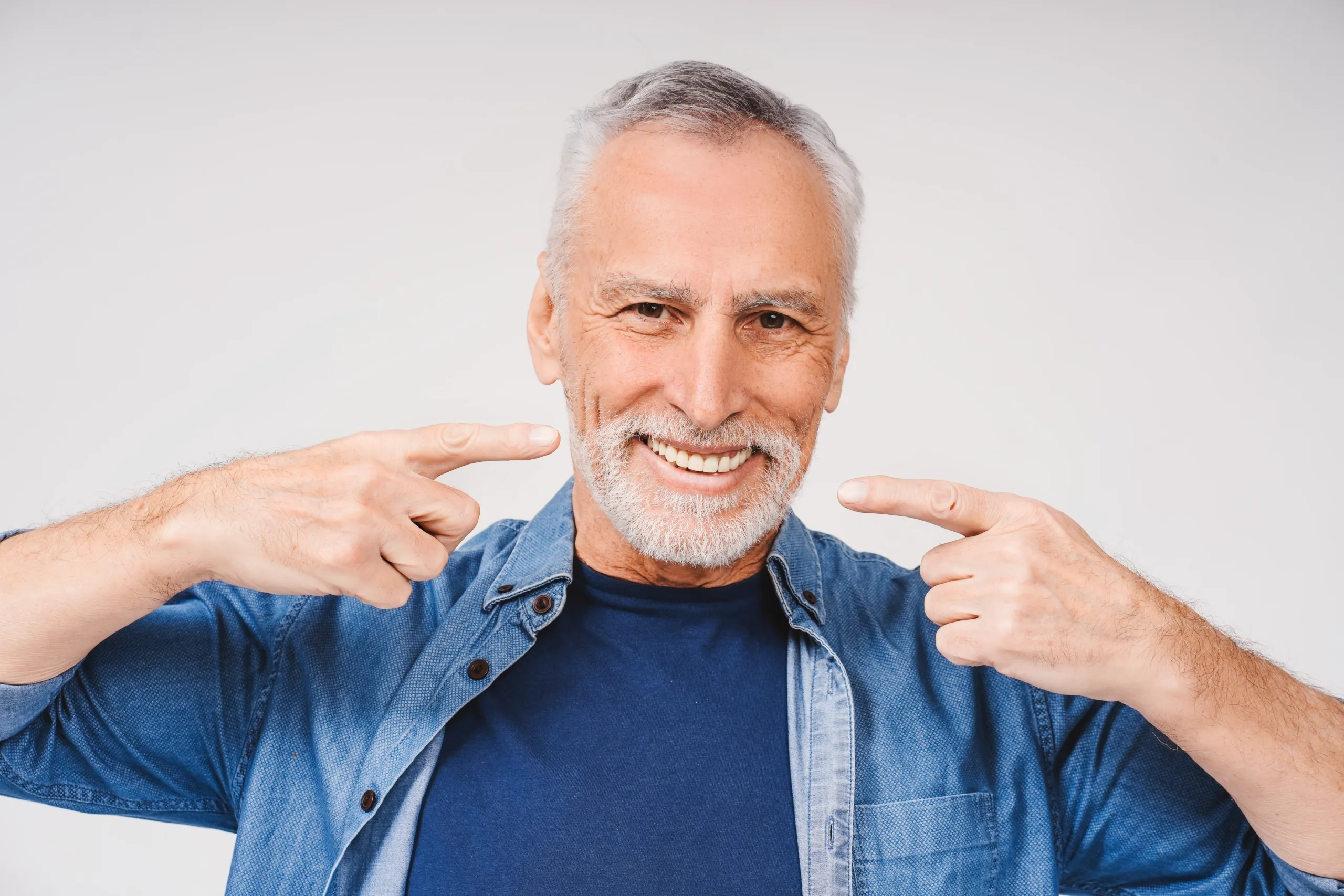 man pointing with hands at teeth looking at camera